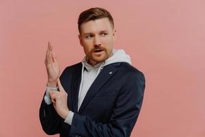 uomo interessato che controlla la sua frequenza cardiaca mentre sta in piedi contro il muro rosa in studio foto