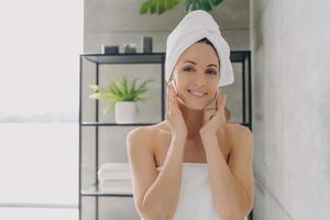 cura della pelle delicata e applicazione cosmetica. la ragazza sta pulendo la pelle con un tonico per il viso e dischetti di cotone. foto