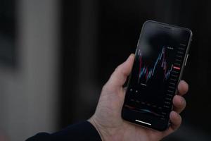 commerciante o investitore controllo azione scambio mercato dati nel mobile App su smartphone foto