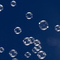 bolle di sapone volanti isolate su sfondo blu. sfondo astratto. foto