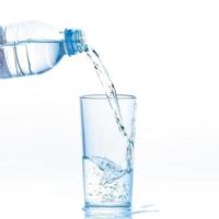 scrosciante puro chiaro acqua a partire dal bottiglia in bicchiere su bianca sfondo. foto