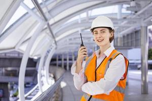 caucasico donna ingegnere è utilizzando walkie talkie mentre ispezionando il costruzione progetto per moderno architettura e vero tenuta sviluppo concetto foto