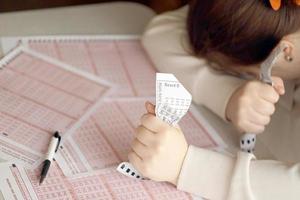 un' triste giovane ragazza soffre a partire dal un' perdita dopo guardare il sfortunato risultato di il lotteria gioco d'azzardo. il concetto di perdente il lotteria e trascorrere i soldi foto
