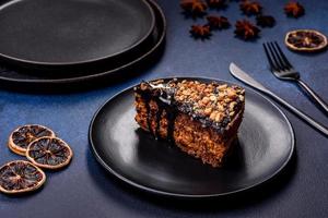 un' pezzo di fresco delizioso torta con noccioline e cioccolato su un' nero piatto contro un' buio blu sfondo foto