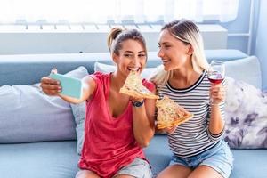 amici mangiare Pizza e sorridente per autoscatto. essi siamo condivisione Pizza e fabbricazione autoscatto foto su mobile inteligente Telefono. essi siamo avendo festa a casa, mangiare Pizza e avendo divertimento.