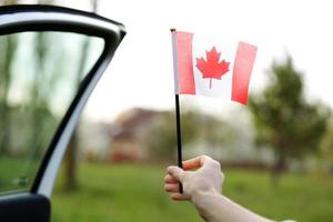 bandiera del canada, simbolo nazionale che sventola contro, giornata di sole. bandiera del canada in mano di donna. messa a fuoco selettiva foto