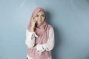 ritratto di un' riflessivo giovane musulmano donna indossare rosa hijab guardare a parte foto