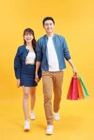 bellissimo giovane coppia con shopping borse. isolato su giallo sfondo foto