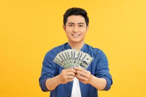 stupito asiatico uomo Tenere grappoli di dollari, fortunato lotteria vincitore foto