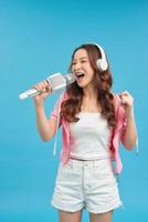 stile di vita ritratto di giovane carino e contento asiatico alunno ragazza cantando in linea karaoke canzone con microfono foto