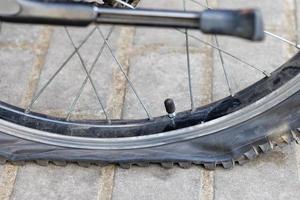 un' forato bicicletta ruota su il sfondo di pavimentazione lastre. foto