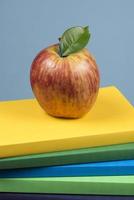 Mela frutta su superiore di un' libro pila, su il indietro di scuola classi. foto