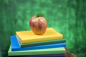 Mela frutta su superiore di un' libro pila, su il indietro di scuola classi. foto