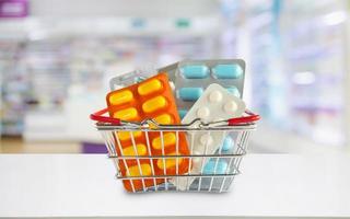 pacchetto di pillole medicinali nel carrello con gli scaffali della farmacia della farmacia sfocano lo sfondo foto
