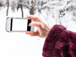 femmina mano prende immagine di smartphone nel inverno foto