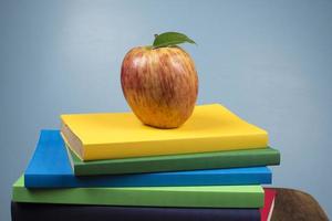 Mela frutta su superiore di un' libro pila, su il indietro di scuola classi. foto