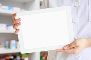 farmacista che mostra tablet computer su sfondo farmacia foto