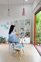 giovane ragazza pittura su carta a casa, legna telaio, hobby e arte studia a casa. foto