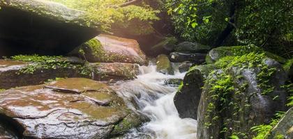un' cascata fluente attraverso rocce entro un' lussureggiante foresta. nel bene kan Provincia, Tailandia foto