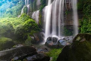 un' cascata fluente attraverso rocce entro un' lussureggiante foresta. nel bene kan Provincia, Tailandia foto