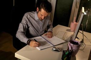 uomo d'affari scrittura rapporti mentre Lavorando in ritardo nel il ufficio. foto