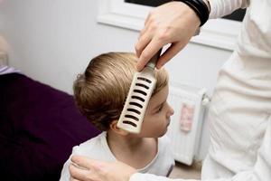 avvicinamento di padre spazzolatura figli maschi capelli. foto