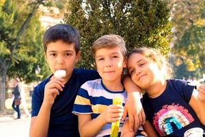 abbracciato bambini mangiare ghiaccio crema nel il città. foto