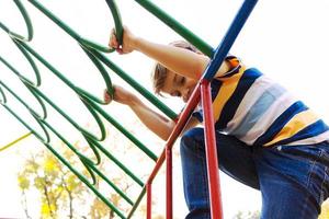 contento ragazzo avendo divertimento su il terreno di gioco a il parco. foto