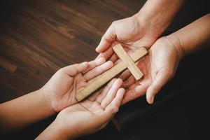 attraversare nel mano preghiera per Dio su buio nel Chiesa concetto per fede spiritualità e religione donna persona preghiere su santo Bibbia nel mattina. cristiano cattolico donna mano con culto nel nero sfondo. foto