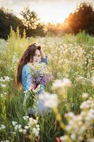 bella ragazza che cammina sul campo in estate con fiori di campo. foto