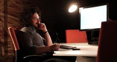 uomo Lavorando su computer nel buio ufficio foto