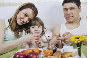 contento giovane famiglia mangiare prima colazione nel letto foto