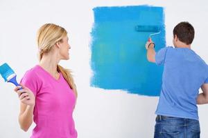 contento coppia dipingere parete a nuovo casa foto