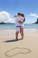 contento coppia avere divertimento su il spiaggia con cuore su sabbia foto