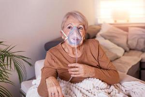 malato anziano donna fabbricazione inalazione, medicina è il migliore medicinale. malato anziano donna indossare un ossigeno maschera e in corso trattamento. anziano donna con un inalatore foto