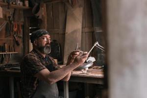 cucchiaio maestro nel il suo laboratorio con di legno prodotti e utensili foto