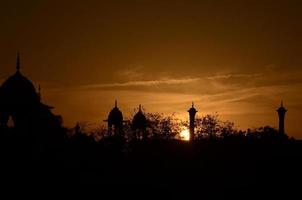 bellissimo tramonto contro il d'oro raggi di un' ambientazione sole come uccelli ritorno per loro tranquillo, calmo nidi. il Mughal architettura sta staglia contro il dorato cielo. foto