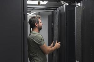 esso ingegnere Lavorando nel il server camera o dati centro il tecnico mette nel un' cremagliera un' nuovo server di aziendale attività commerciale mainframe supercomputer o criptovaluta estrazione azienda agricola. foto