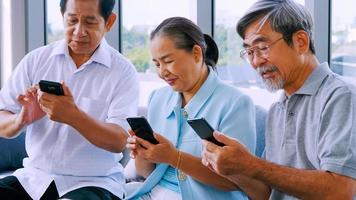 gruppo di anziano amici utilizzando inteligente Telefono nel un' la pensione casa foto