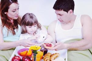 contento giovane famiglia mangiare prima colazione nel letto foto