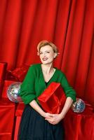 maturo elegante elegante donna con regalo scatola su rosso sfondo. festa, moda, celebrazione, anti età concetto. foto