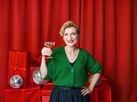 maturo elegante elegante donna con bicchiere di scintillante vino su rosso sfondo. festa, moda, celebrazione, anti età concetto foto