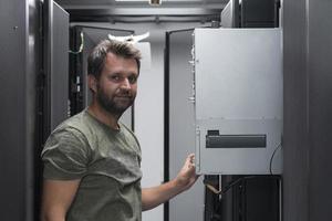 esso ingegnere Lavorando nel il server camera o dati centro il tecnico mette nel un' cremagliera un' nuovo server di aziendale attività commerciale mainframe supercomputer o criptovaluta estrazione azienda agricola. foto