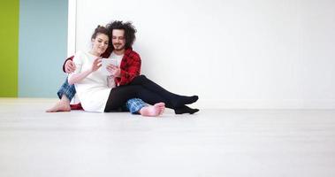 giovane coppia utilizzando digitale tavoletta su il pavimento foto