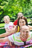 felice giovane coppia con i loro bambini si divertono al parco foto