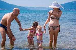 contento famiglia spruzzi ogni altro a spiaggia foto