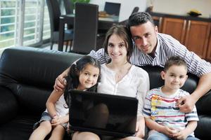 contento giovane famiglia avere divertimento e Lavorando su il computer portatile a casa foto