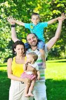felice giovane coppia con i loro bambini si divertono al parco foto