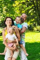 felice giovane coppia con i loro bambini si divertono al parco foto