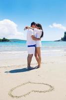 contento coppia avere divertimento su il spiaggia con cuore su sabbia foto